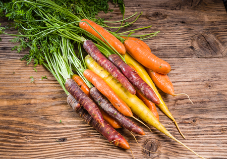 Bunch of colorful fresh carrots on a rustic wooden tableの写真素材