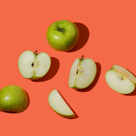 Green apples on orange background. Minimal food concept. Flat lay, top viewの素材
