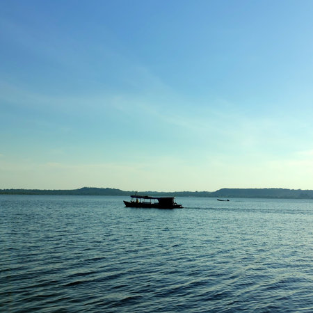 Silhouette of boat on the sea with blue sky background.