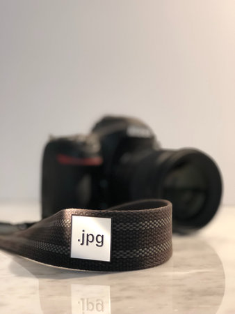 Black belt with photo camera on white background. Selective focus.