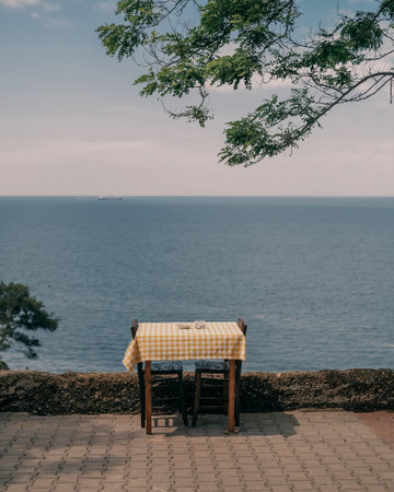 Table and chairs on the terrace overlooking the sea in a summer dayの写真素材