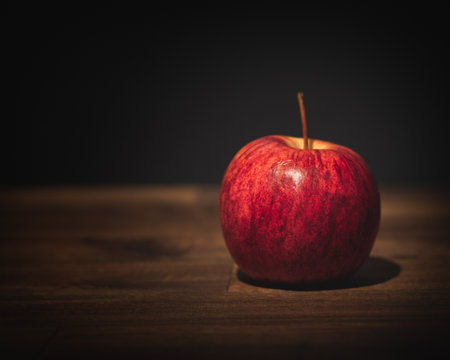 Red apple on a wooden table with dark background. Selective focus. Toned.の写真素材
