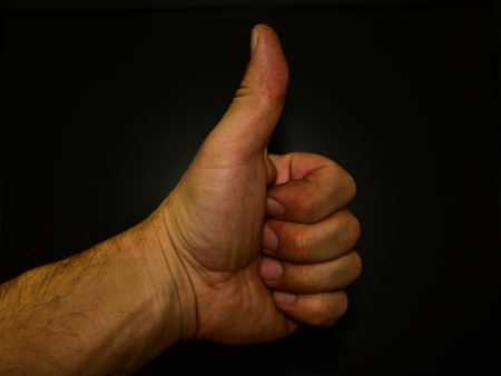 thumbs up on a black background goodの写真素材