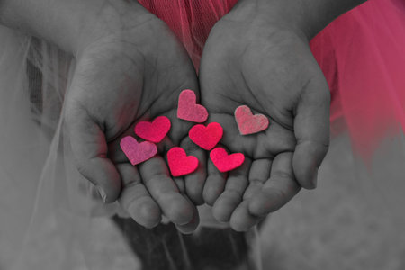 Children's hands holding the heart on a pink background. Concept of love, care, faith, hope, purityの写真素材