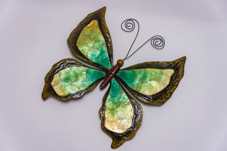 Butterfly made of brown metal on an old, bright wooden wall Metal butterfly on a white wallの写真素材