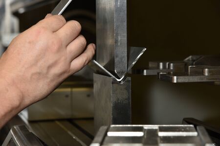 worker operating metal press machine at workshop. Bending of metal on the machine.の写真素材