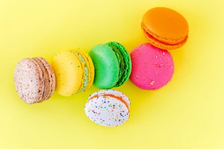 Sweet colorful French macaroon biscuits on pastel yellow background, top viewの写真素材