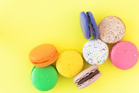 Sweet colorful French macaroon biscuits on pastel yellow background, top viewの写真素材