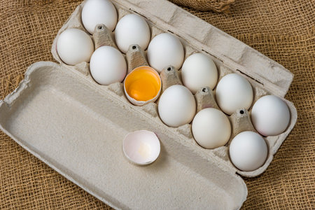 White eggs in carton with broken egg A dozen white eggs