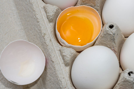 White eggs in carton with broken egg A dozen white eggs
