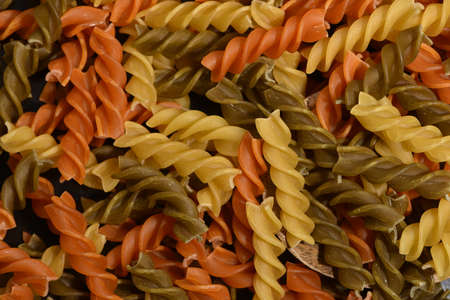 Composition of raw pasta uncooked tricolore fusilli, pasta twist shape. Close up and selective focus on colorful fusilli pasta. Twisted colored pasta in Italy.の写真素材