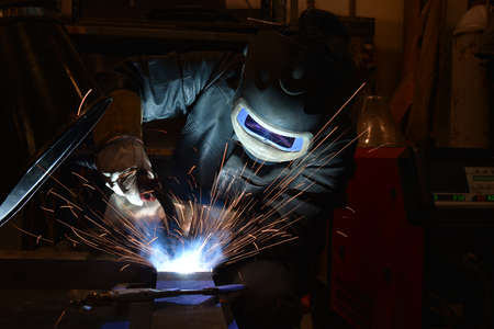 worker with protective mask welding metal and sparks. The welder is welding metal.の写真素材