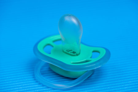 Baby pacifier on blue background, Pacifier on a blue background with a rattle.
