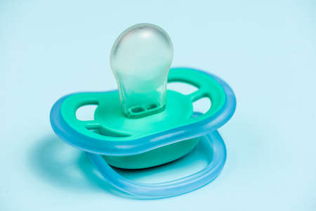 Blue-green Turquoise baby's pacifier on a soft blue background.の写真素材
