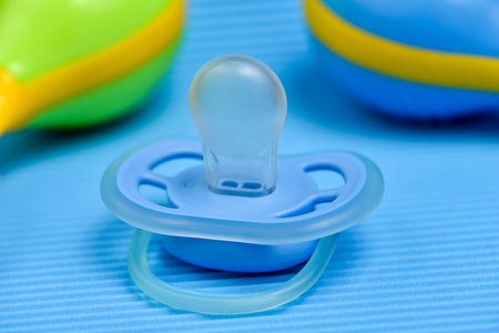 Baby pacifier on blue background, Pacifier on a blue background with a rattle.