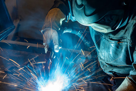 Workers wearing industrial uniforms and Welded Iron Mask at Steel welding plants, industrial safety...