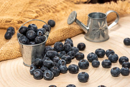 Freshly picked blueberries in wooden bowl. Juicy and fresh blueberries with green leaves on rustic table. Bilberry on wooden Background. blueberry antioxidant.の写真素材