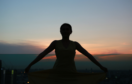 Silhouette of woman stretching arms enjoy relax at sunset on rooftop of the buildingの写真素材