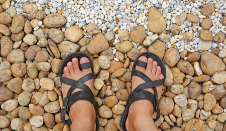 Looking down at the feet on a gravel stones decorate in the gardenの写真素材