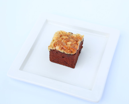 chocolate brownies on white square plate, Brownie cake topped with nutsの写真素材