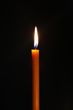 One light candle burning brightly in the black backgroundの写真素材