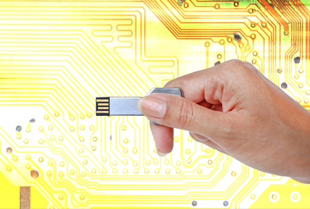 Key USB data storage in hand against bright light and circuit background.