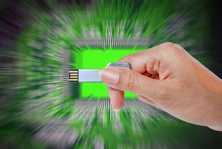 Hand holding USB data storage against bright light and circuit background.の写真素材