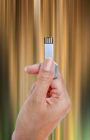 Key USB data storage in hand against bright light and circuit background.の写真素材