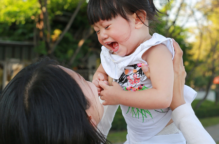 Close-up mother carrying her little girl and crying in parkの写真素材
