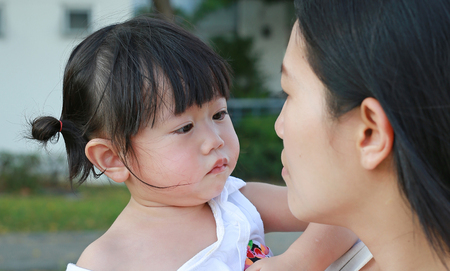 Close-up mother carrying her little girl and crying in park