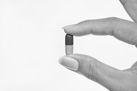 Finger holds pill on white background, Black and white toneの写真素材