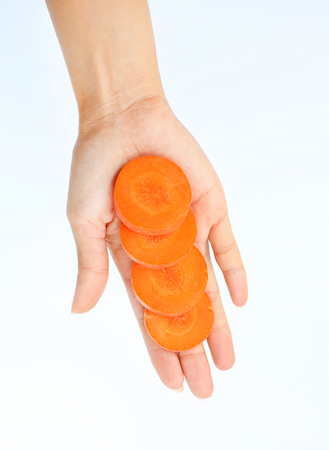 Slice of carrot in woman's hand on white backgroundの写真素材