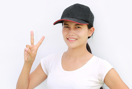 Close up young asian woman wear T-Shirt and cap Showing expression a two-finger victoryの写真素材