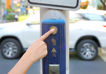 female hand pushing button for traffic lightの写真素材