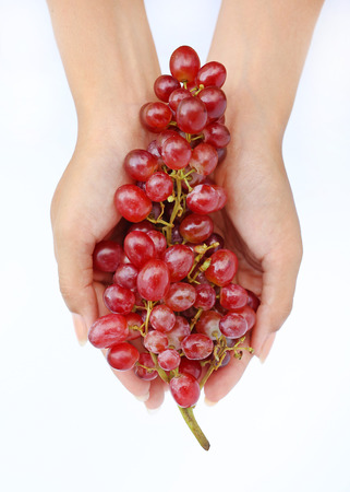 Hand holding bunch red grape on white background.の写真素材