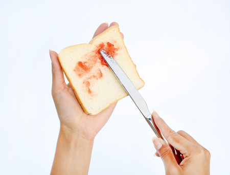 Hand holding bread and Strawberry jam making for breakfast on white backgroundの写真素材