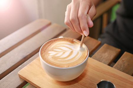 Hot latte coffee with hearts pattern and syrup on wooden table.の写真素材