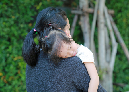 Mother carries the sleeping child girl in her arms.の写真素材