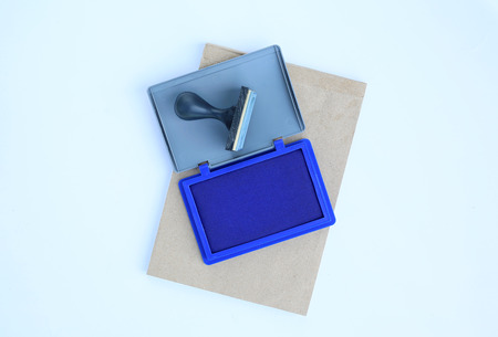 Rubber stamp and Blue Ink cartridges on brown book against white background.の写真素材