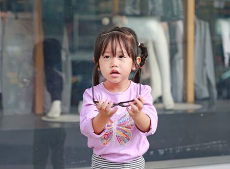 Portrait of cute little girl trying to wear glassesの写真素材