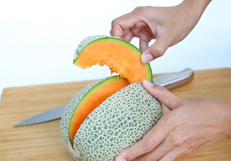 Sliced cantaloupe melon in hand on wood boardの写真素材