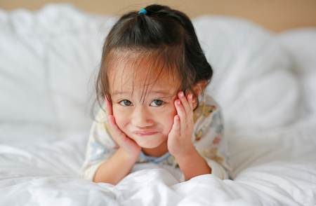Cute little girl lying on bed at the morningの写真素材