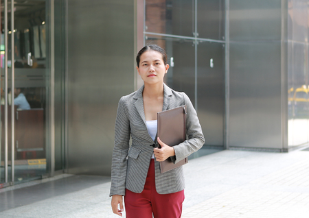 Beautiful young business woman walking outside. Asian businesswoman office worker in downtown business district.の写真素材
