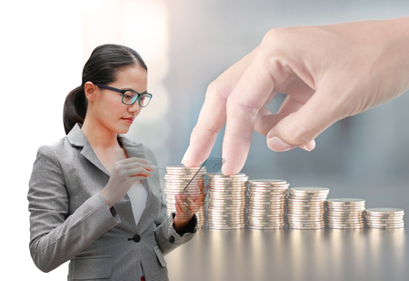 Double exposure young Business woman using smartphone with image of finger walking up stack of coins. Saving money concept.の写真素材