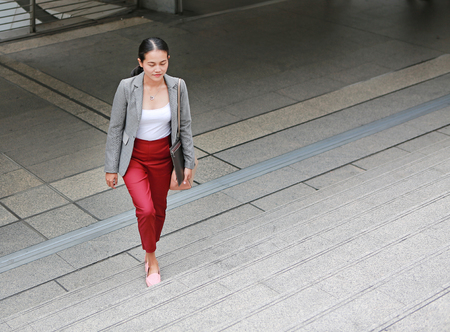 Beautiful young business woman walking outside. Asian businesswoman office worker in downtown business district.の写真素材