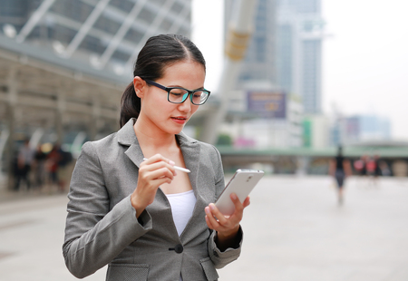 Beautiful business woman working on a smartphone in her hands outdoors.の写真素材