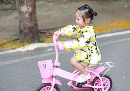 Cute little child girl riding bike in parkの写真素材