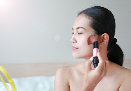 Portrait of attractive young adult woman applying blusher.の写真素材