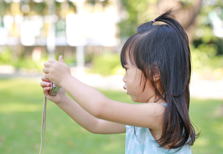 Child girl taking pictures on camera in the garden, Focus at cameraの写真素材