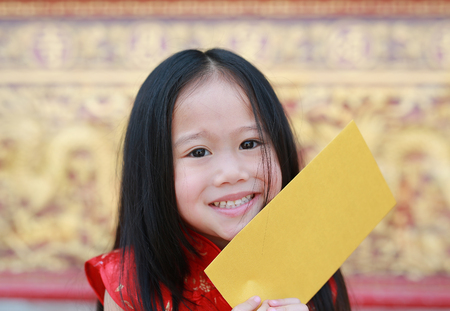 Close-up face of smiling little asian girl holding a gold envelope. Happy chinese new year.の写真素材